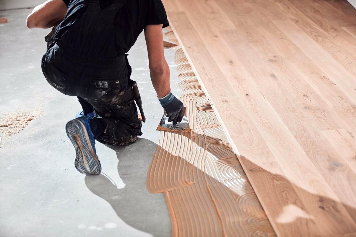 Professional handyman installing laminate flooring in a new apartment