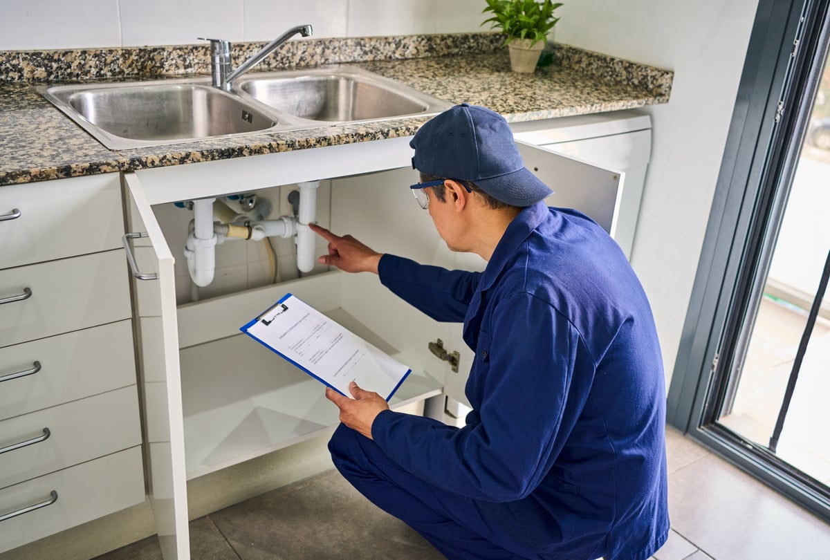 Plumber inspecting maintenance with clipboard at home renovation checking service quality