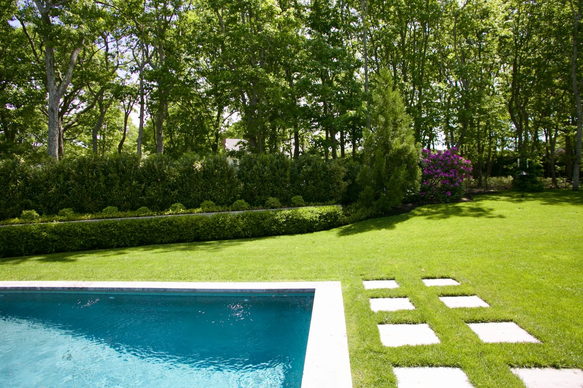 Rectangular swimming pool with bluestone coping and stepping stone pavers in manicured lawn at a Hamptons residence