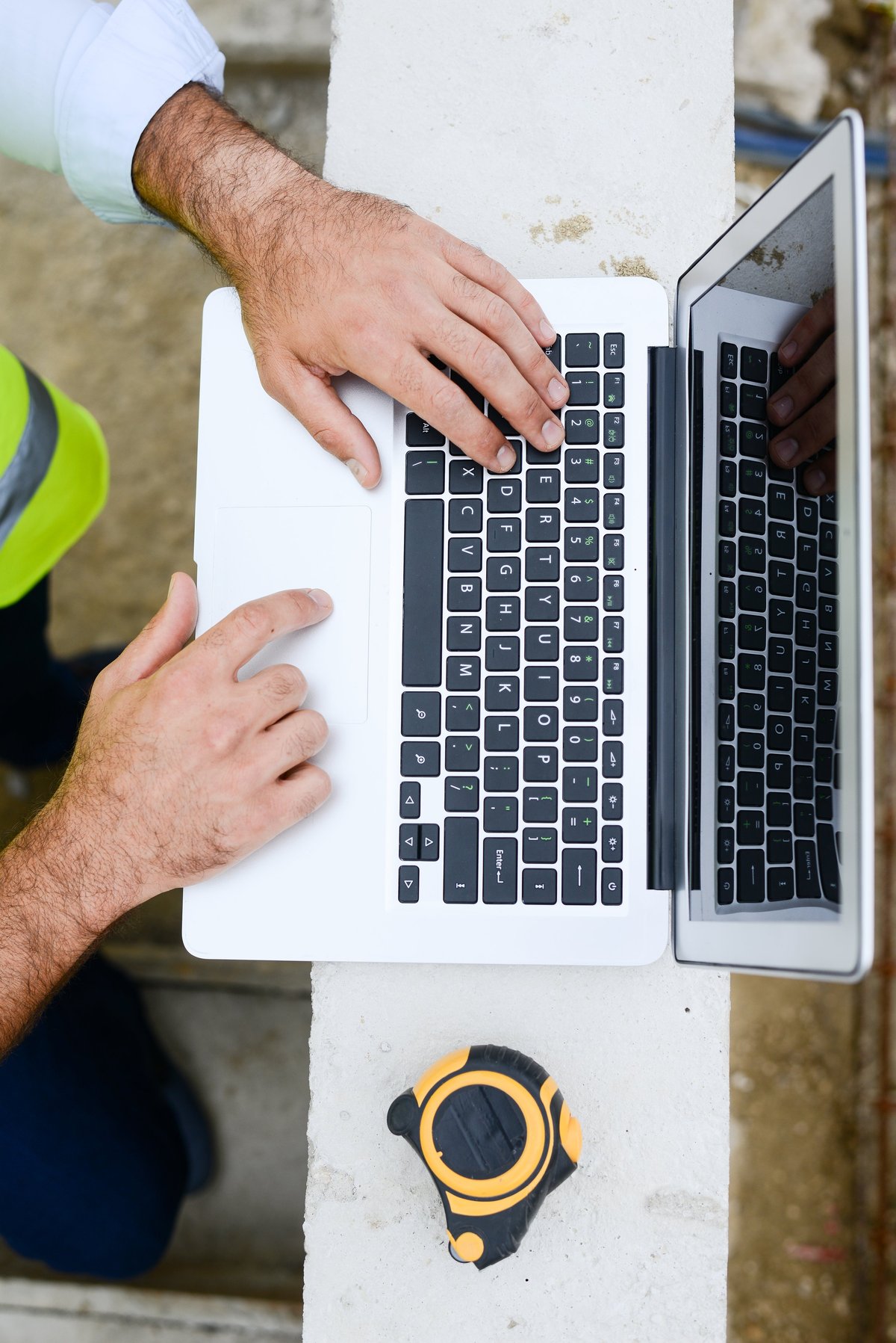 Foreman architect working on a laptop at a new house construction site with framing in progress